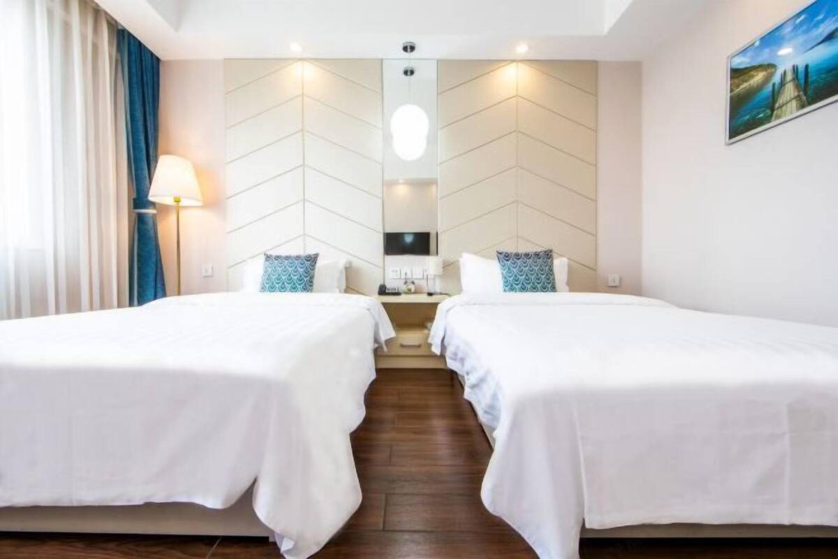 Ein Hotelzimmer mit zwei Betten, einem großen Spiegel, einer Lampe und einem Bild an der Wand.
