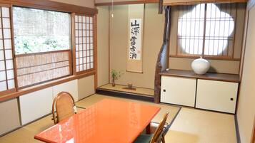 A traditional Japanese room with tatami flooring, a low orange table, and sliding doors with bamboo frames.