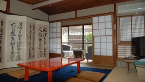A traditional Japanese room with tatami flooring, a sliding door, and a table with calligraphy. - Yadoya Manjiro (Kyoto)