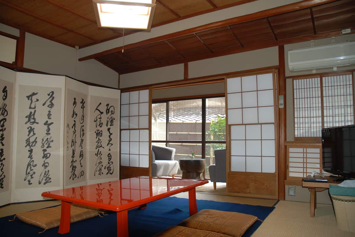 A traditional Japanese room with tatami flooring, a sliding door, and a table with calligraphy.