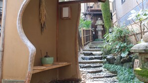 A narrow stone staircase leading up to a traditional wooden building with a tiled roof. - Yadoya Manjiro (Kyoto)