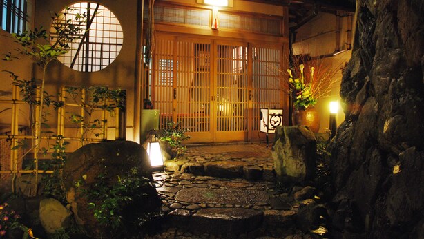 A traditional Japanese building with a wooden gate, stone pathway, and potted plants. - Yadoya Manjiro (Kyoto)