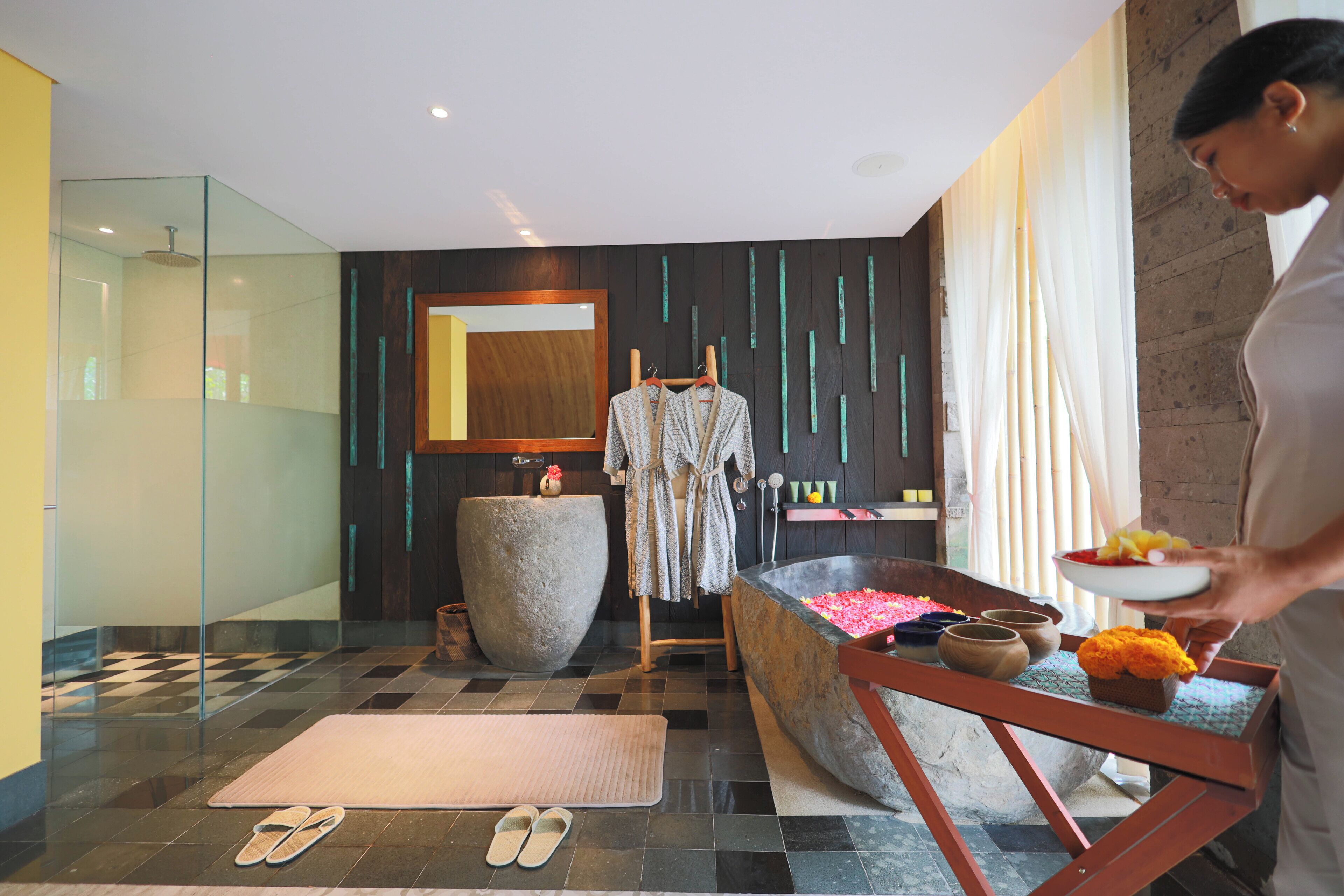 A modern bathroom with a checkered floor, a large stone basin, and a wooden bench.
