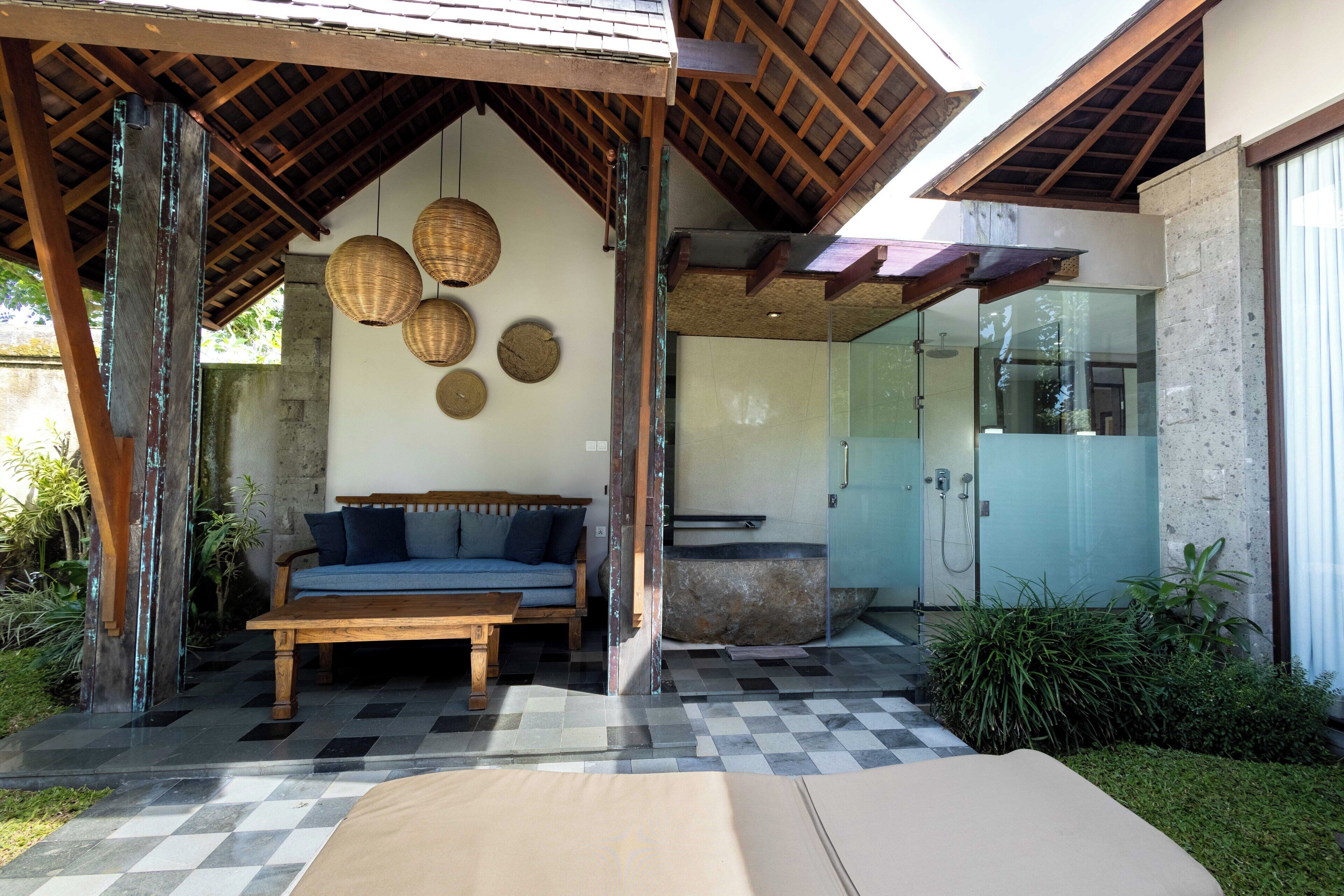 A covered outdoor seating area with a checkered floor, a wooden bench, and a sofa.