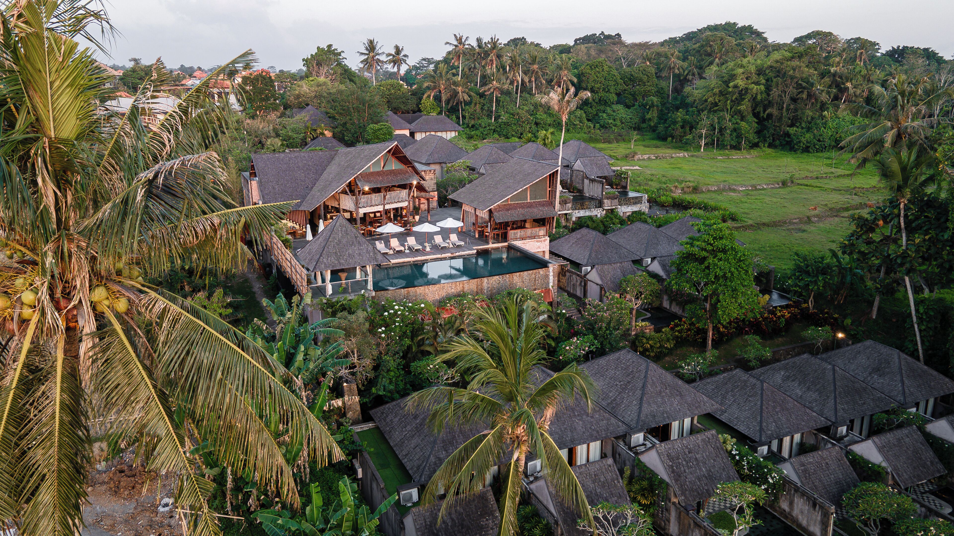 A resort with multiple bungalow-style buildings, a central pool area, and lush surrounding vegetation.