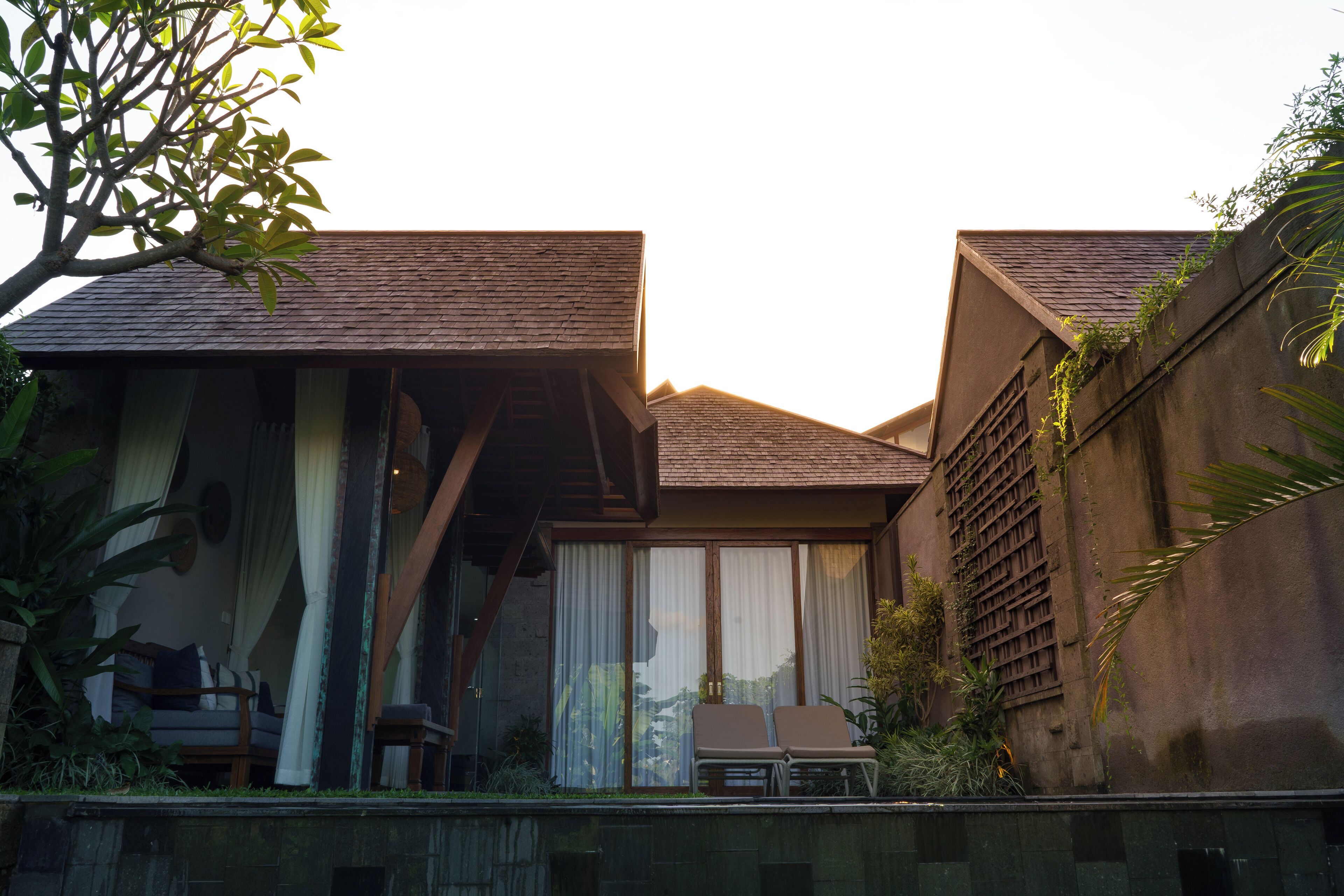 A modern villa with a balcony, a dining area, and a view of the surrounding greenery.