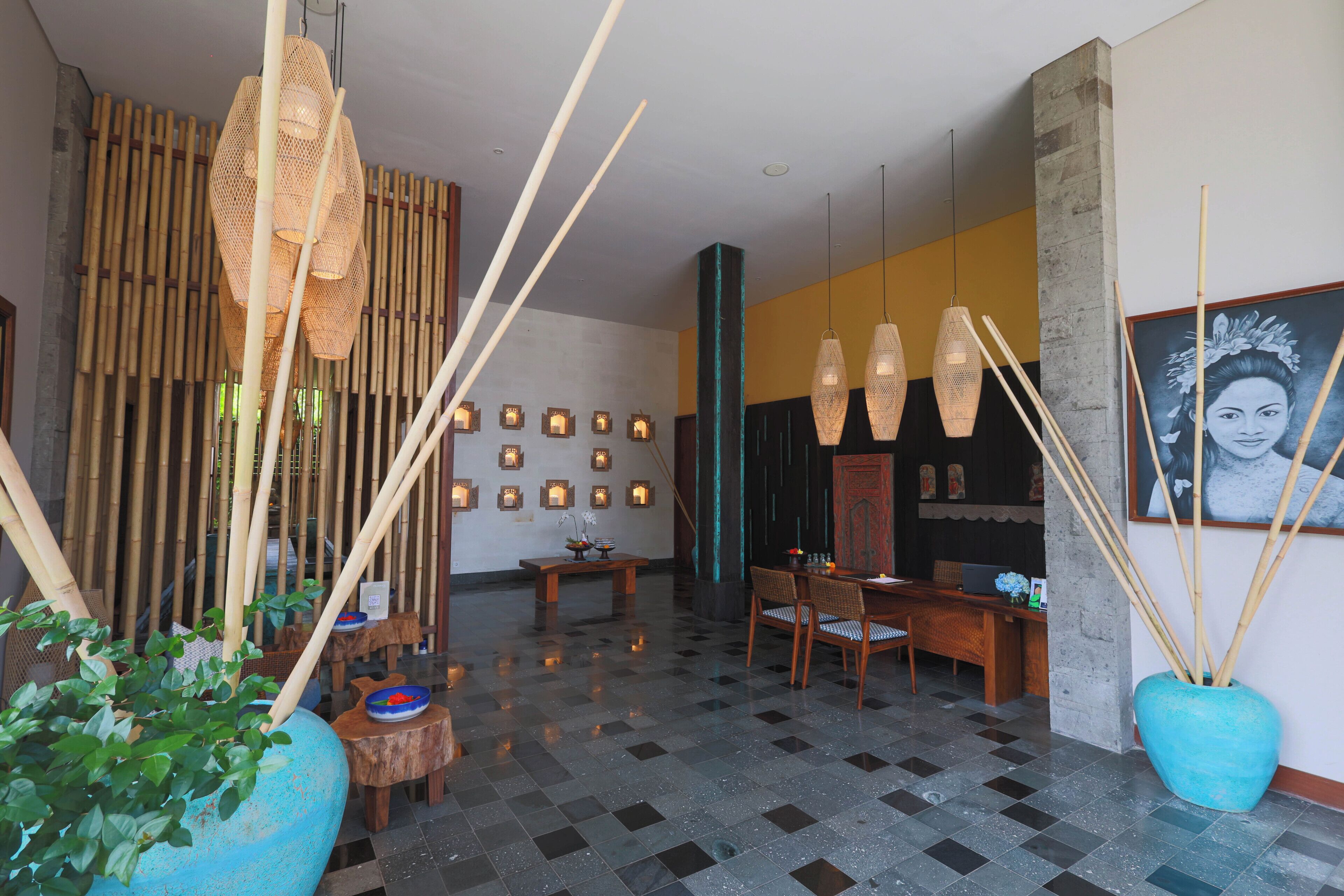 A lobby with a checkered floor, bamboo decor, a reception desk, and wall-mounted lights.