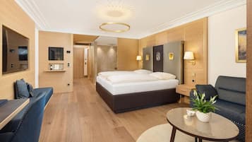 A modern hotel room with a large bed, a sofa, a small table, and a mirror.