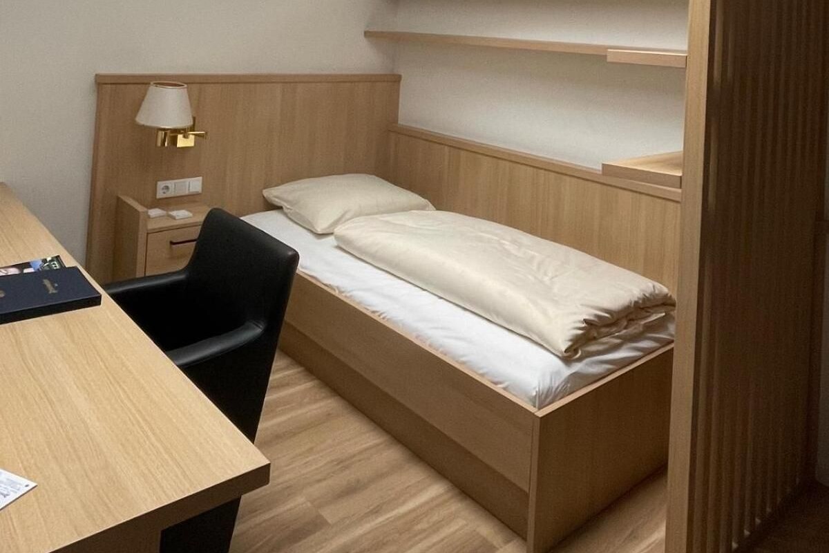 A compact room with a skylight, a bed, a desk, and a chair.