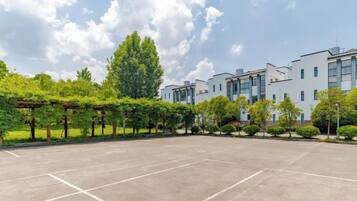 A courtyard with a paved area, trees, and a building with multiple windows.