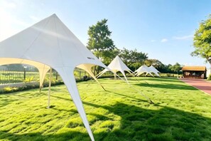 A grassy area with multiple white tents. - Huangshan Scholars Conference Hotel (Xiuning)