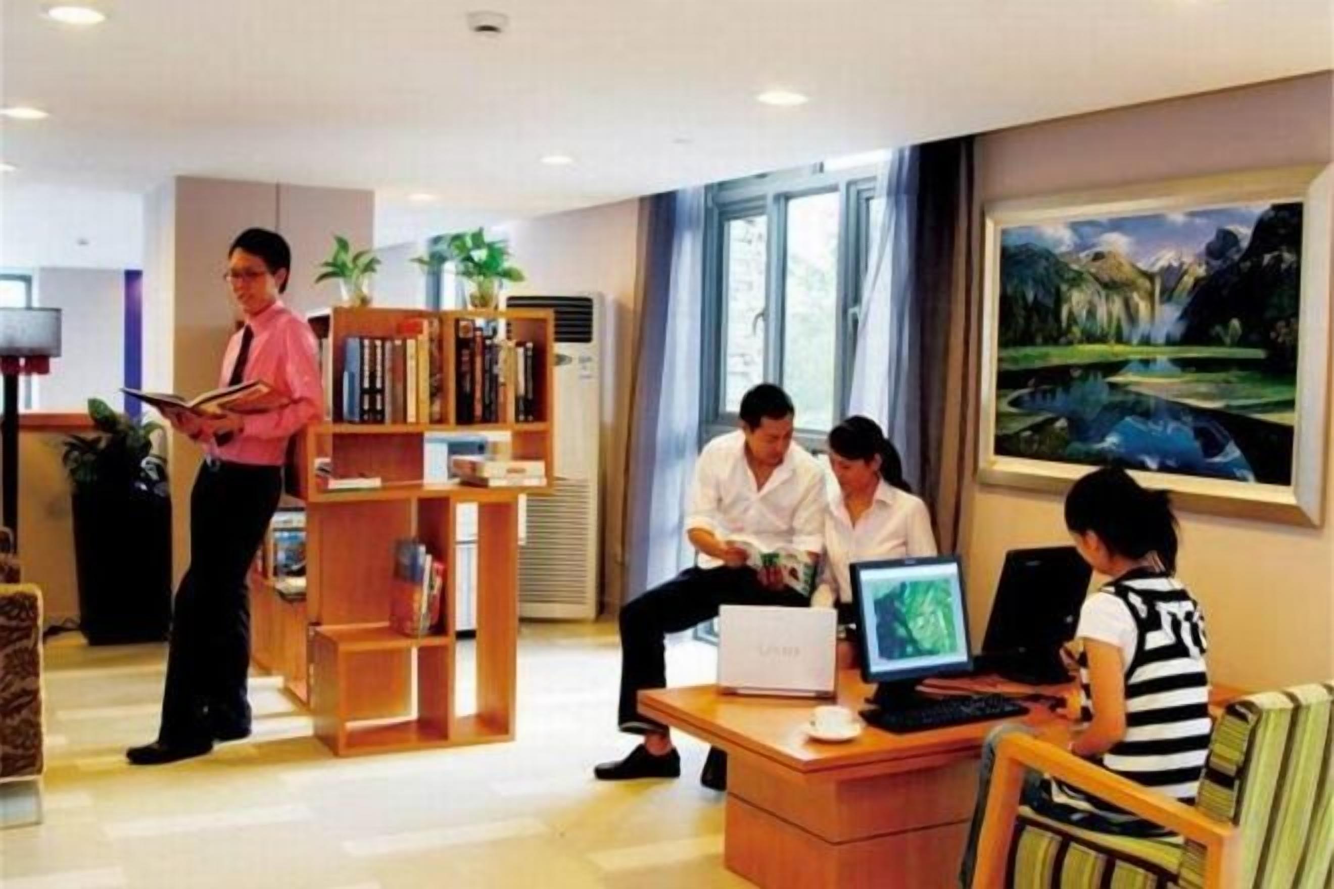 Eine Hotelhalle mit einer Rezeption, einer Sitzecke und einem Bücherregal.