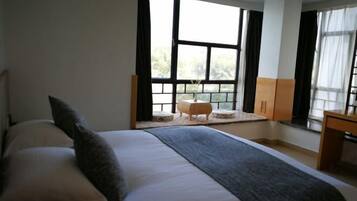 A bedroom with a large bed, a small table, and a window with curtains.