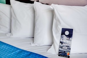 A bed with white pillows and a blue blanket. There is a sign on the bed with the text "RESTING FOR THE JOURNEY AHEAD" and a picture of a road with a car. - Super 8 by Wyndham St. Petersburg (St. Petersburg)