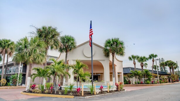 A hotel with a central American flag, palm trees, and a fountain.