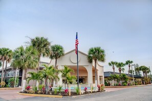 A hotel with a central American flag, palm trees, and a fountain. - Super 8 by Wyndham St. Petersburg (St. Petersburg)