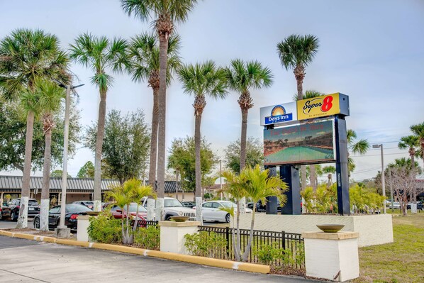 A hotel with a large signboard, palm trees, and parked cars. - Super 8 by Wyndham St. Petersburg (St. Petersburg)