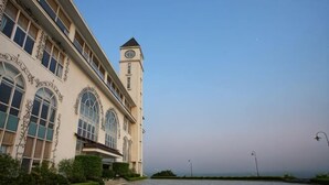 Un bâtiment doté de grandes fenêtres en arc de cercle, d’une tour horloge et d’un sol à motifs.