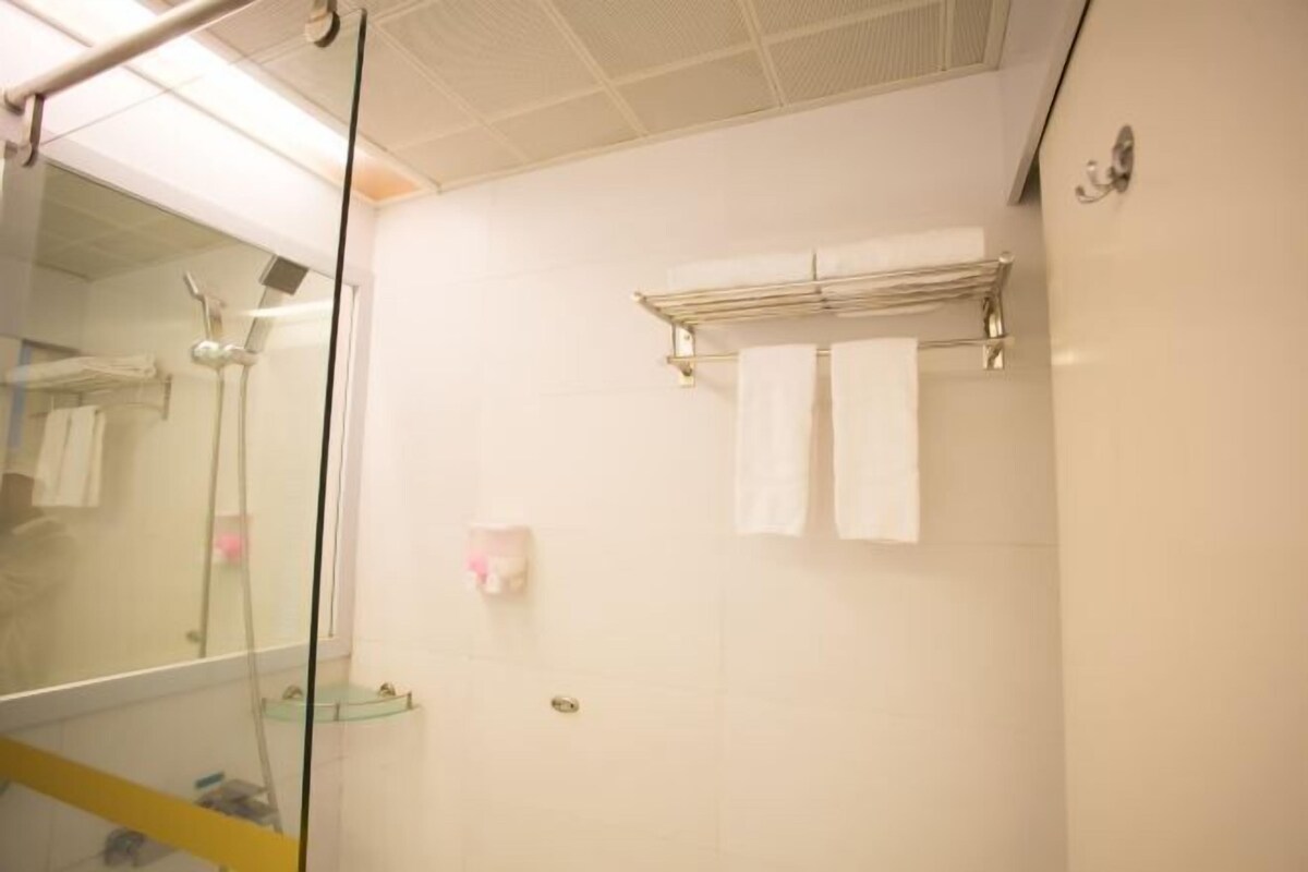 Ein Badezimmer mit Duschkabine aus Glas, einem Handtuchhalter und einer kleinen Ablage für Toilettenartikel.
