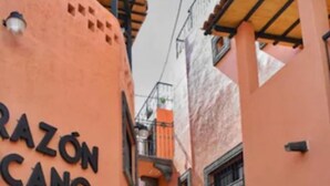 Una calle estrecha con edificios pintados en tonos cálidos, mostrando un letrero que dice "RAZÓN CANO".