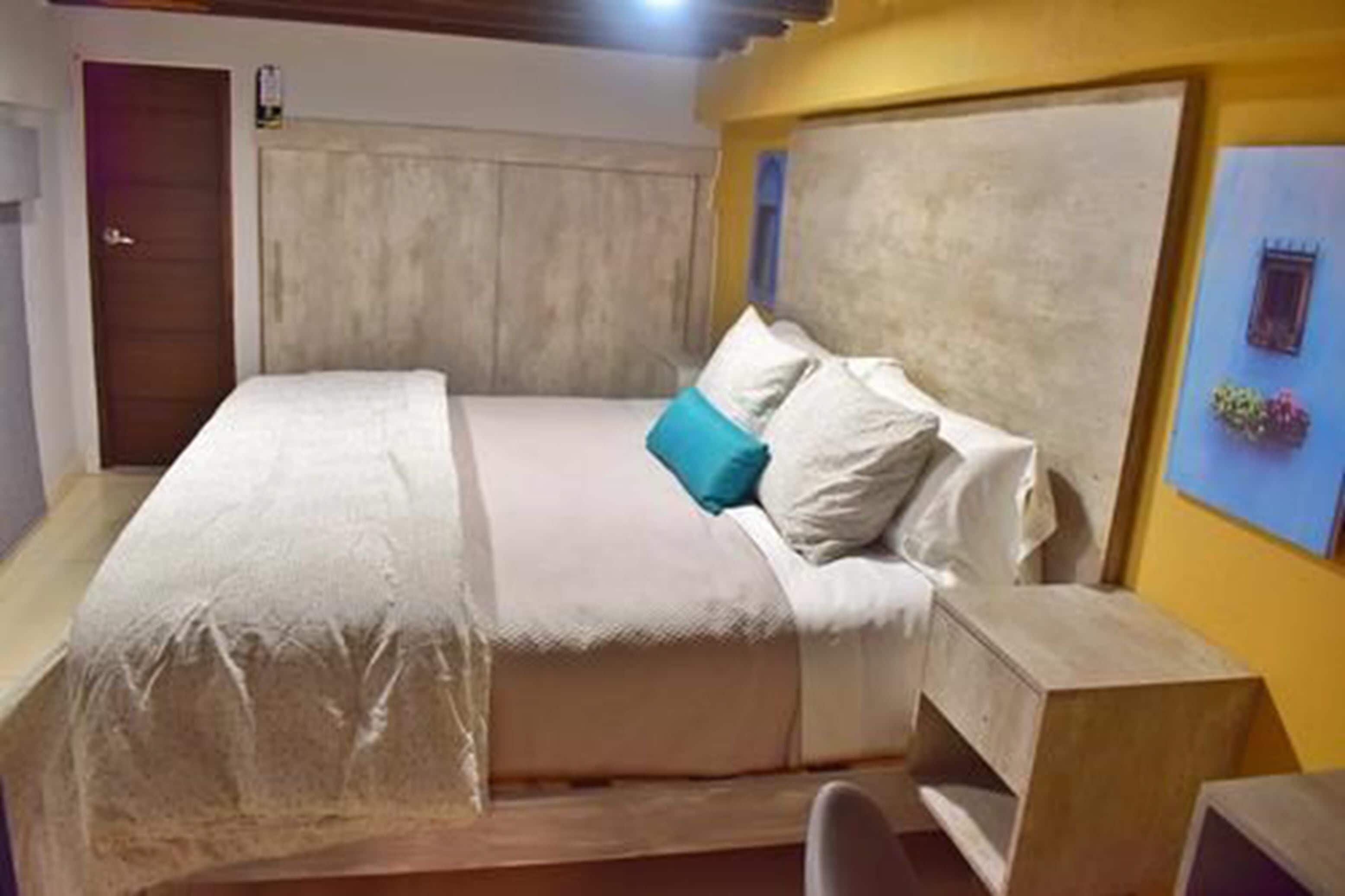 A bedroom with a bed, a wooden headboard, a bedside table, and a chair.