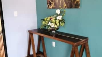 Une console en bois sur laquelle est posé un vase de fleurs, le tout placé devant un mur de couleur turquoise.