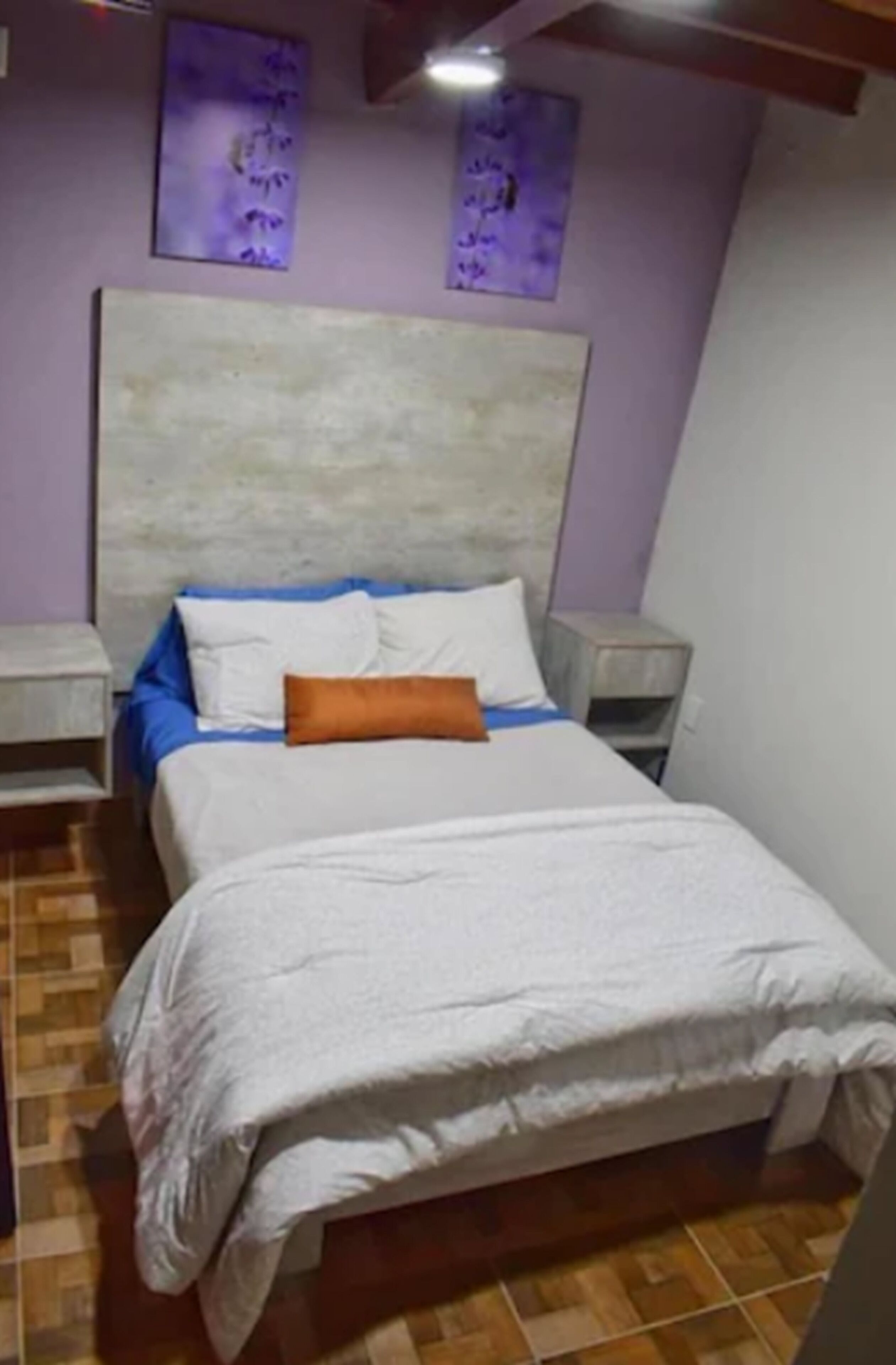 A bedroom with a bed, two nightstands, and a headboard.