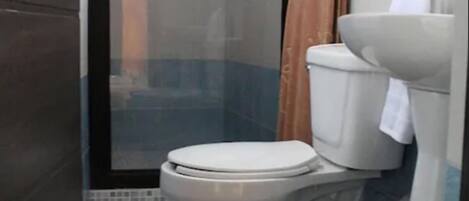 A bathroom with a toilet, a shower enclosure, and a sink.