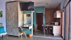 Una cocina moderna con comedor, un televisor en la pared y una puerta corredera que da a otra habitación.