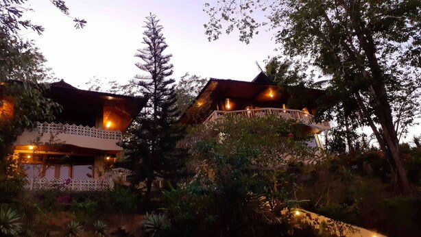 A two-story building with a balcony, surrounded by trees and plants. - Tangkoko Sanctuary Villa & Spa (Bitung)