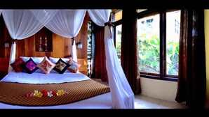 A bed with a canopy, a wooden headboard, and a floral bedspread. - Tangkoko Sanctuary Villa & Spa (Bitung)