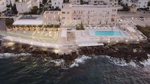 Un hotel frente al mar con piscina, zona de estar al aire libre y costa rocosa.