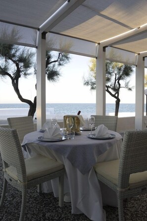 A table set for two with a view of the sea, white wicker chairs, and a white tablecloth. - Hotel La Sorgente (Fasano)