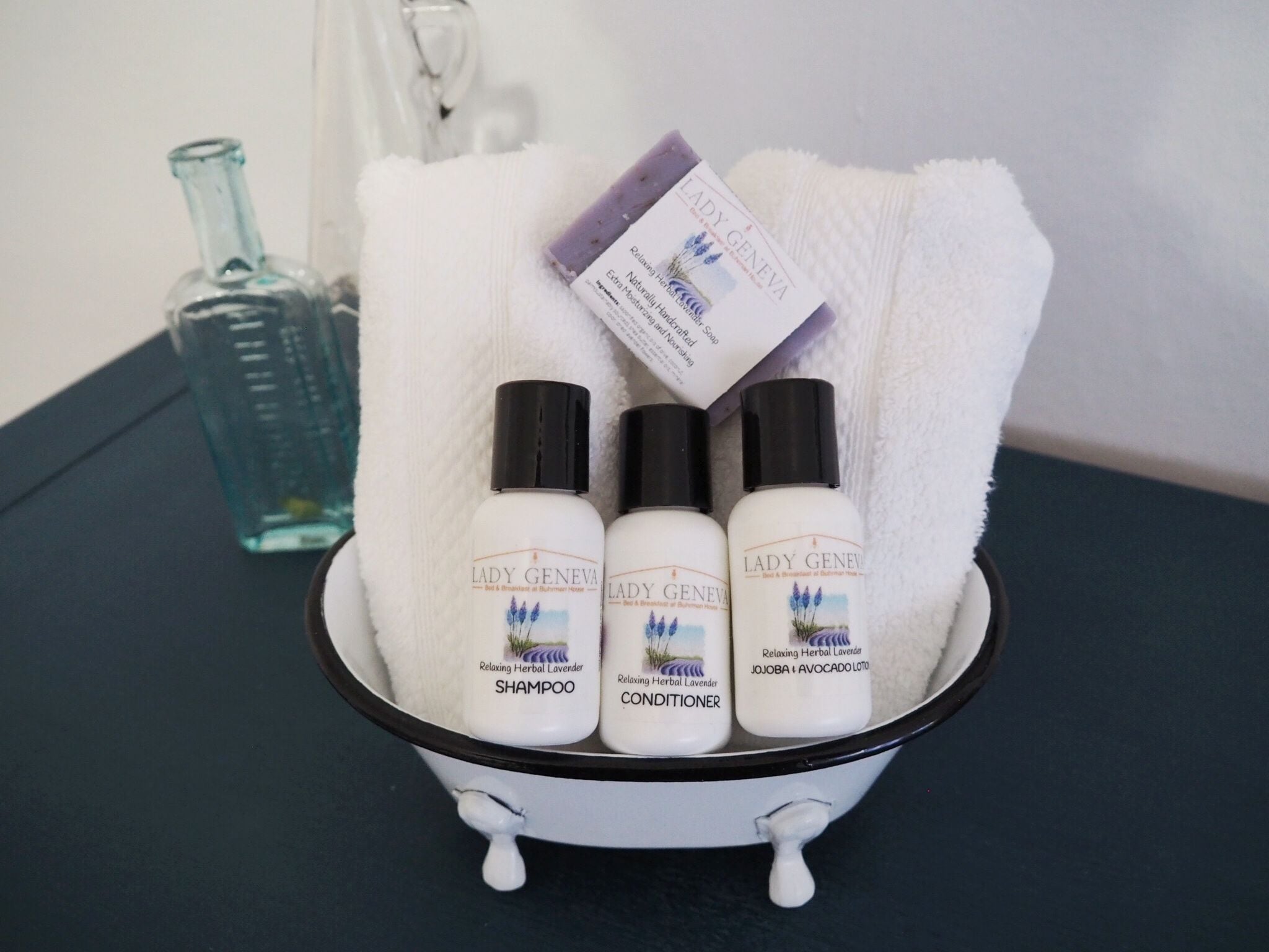 Ein Waschbecken mit drei Produkten von Lady Geneva: Shampoo, Conditioner und Lotion.
