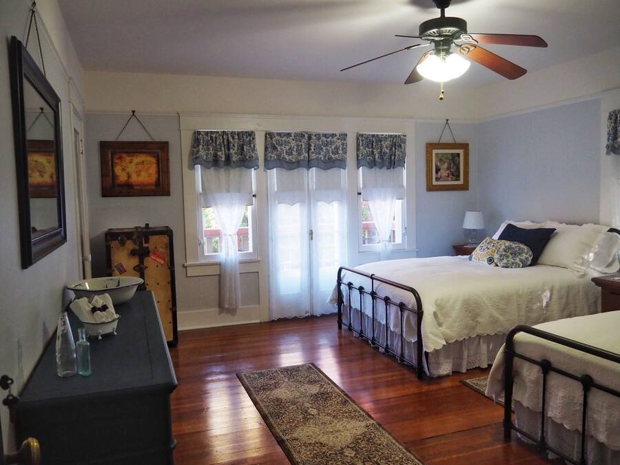 A bedroom with a bed, a nightstand, a dresser, a ceiling fan, and a window with curtains.
