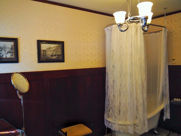 Une salle de bain avec une baignoire, un miroir et deux tableaux encadrés au mur.