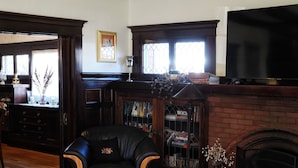 Un salón acogedor con chimenea, un sillón de cuero y una estantería llena de libros.