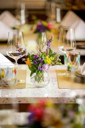 A table set with clear glassware and a centerpiece of flowers.