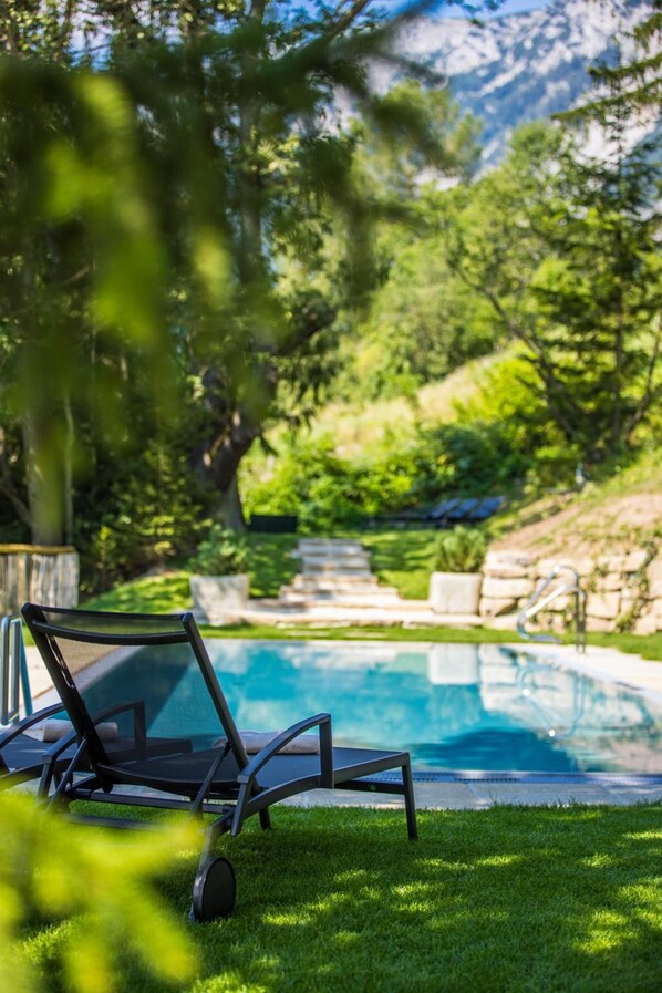 A pool area with lounge chairs and a clear view of a mountainous landscape.