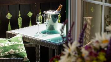 A patio with a table set for two, a champagne bottle, and a view of mountains.