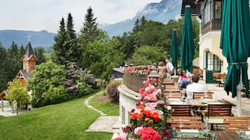 Un restaurante con terraza al aire libre y vistas a un paisaje montañoso.