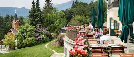 A restaurant with outdoor seating overlooking a mountainous landscape.