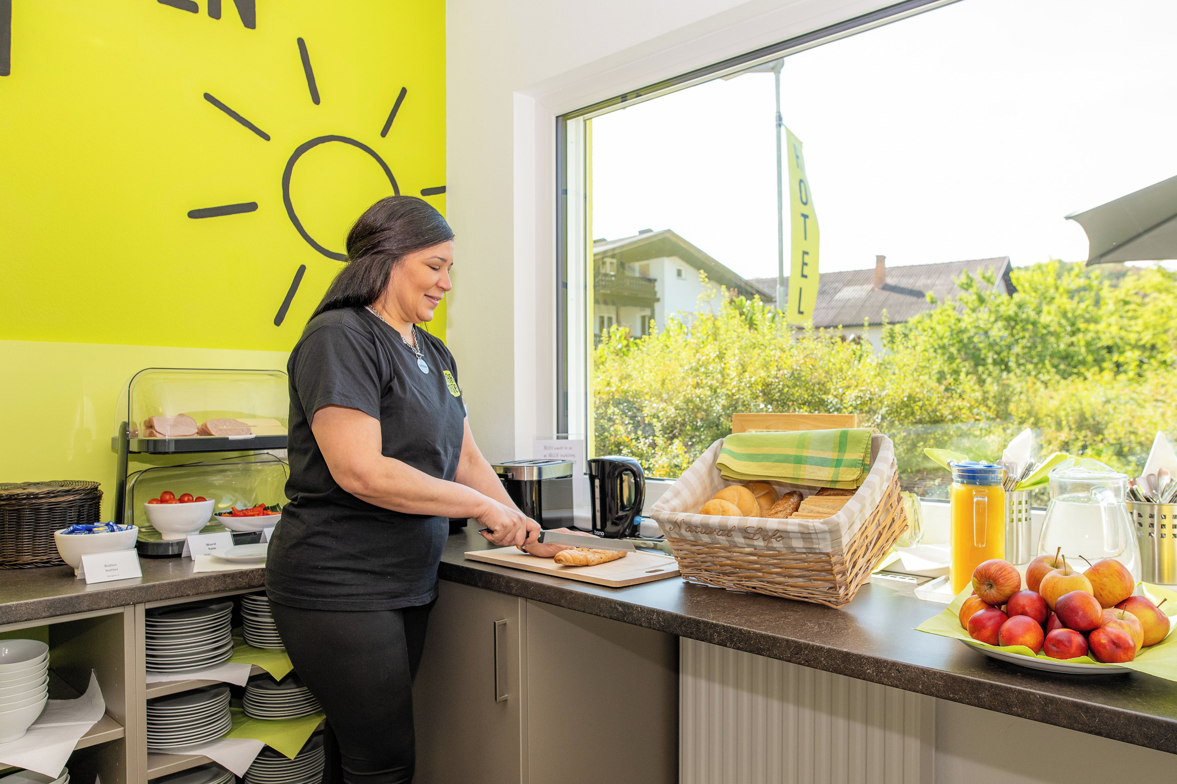 Frühstücksbuffet mit Brötchenkorb, Apfelplatte und Kaffeemaschine.