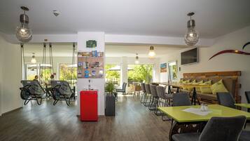 Uma área de refeições moderna com mesa de madeira, cadeiras e uma geladeira vermelha.