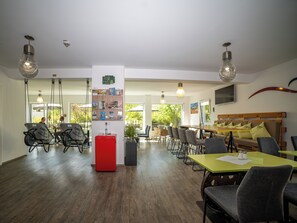 A modern dining area with a wooden table, chairs, and a red refrigerator. - Smart Motel (Gars am Kamp)