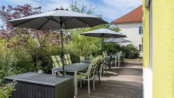 An outdoor patio with tables and chairs, umbrellas, and a wooden deck.