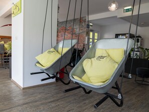 Two hanging chairs with yellow cushions in a modern interior with a brick wall and wooden flooring. - Smart Motel (Gars am Kamp)