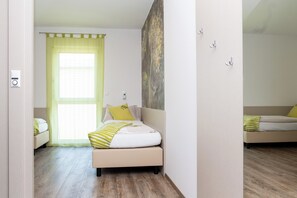 A bedroom with a bed, a window with a curtain, a painting on the wall, and a bedside table. - Smart Motel (Gars am Kamp)
