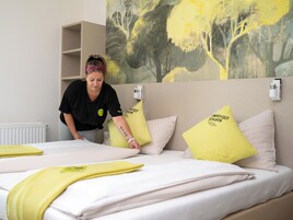 Una habitación de hotel con cama, almohadas y un cuadro en la pared.