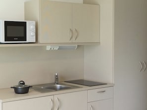 A kitchen with a microwave, a sink, and a stove. - Smart Motel (Gars am Kamp)